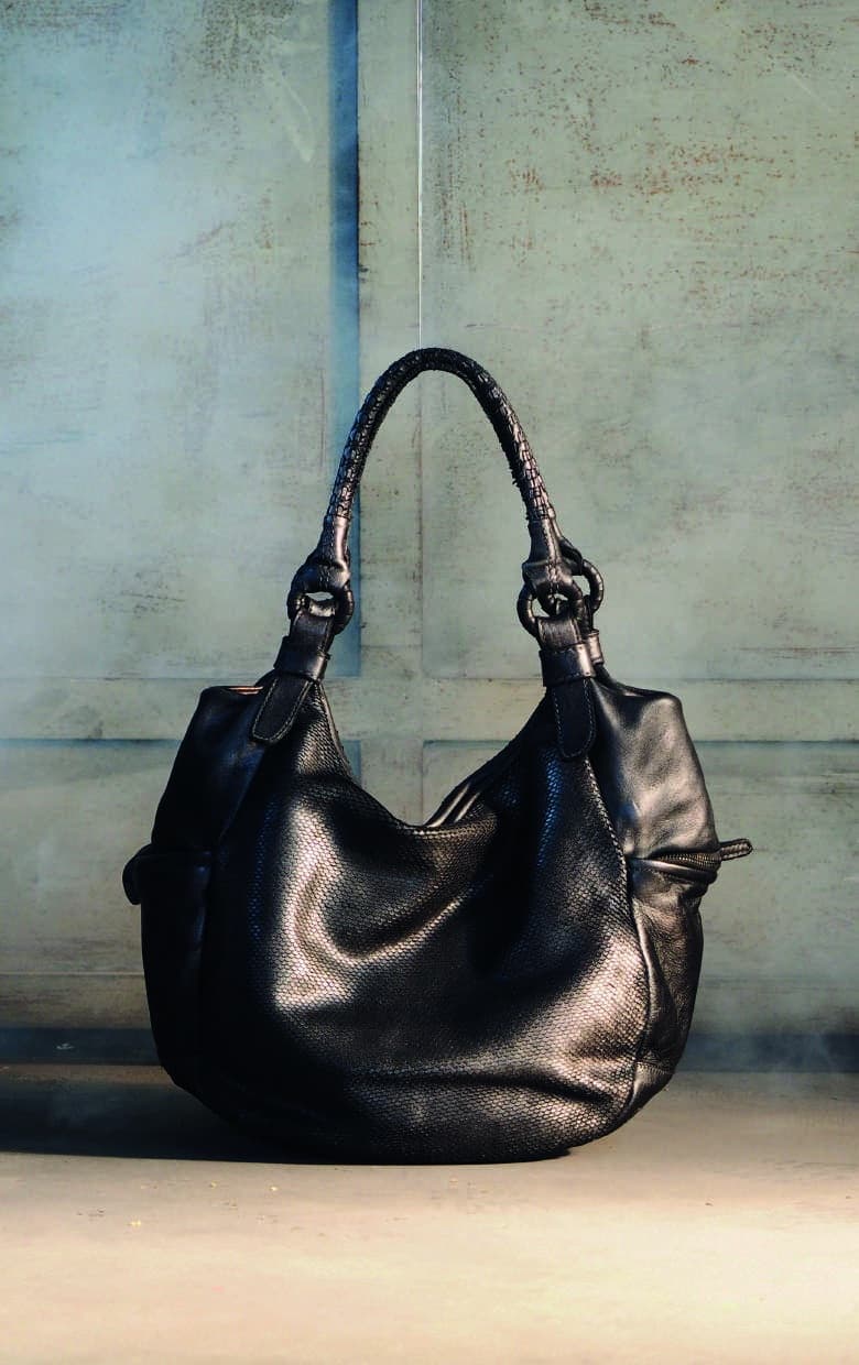 Still life di una borsa in pelle nera su fondo materico